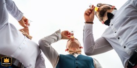 In Sarrebourg, France, the groom shares a drink with his witnesses in a candid behind-the-scenes photo captured at the wedding venue, showcasing a moment of camaraderie and celebration.